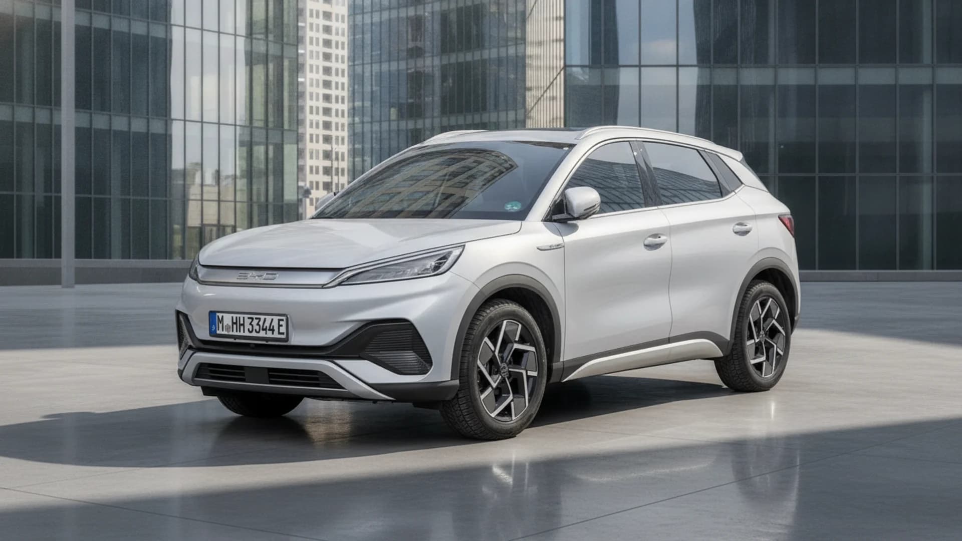 A silver SUV is parked on a light gray surface, with modern glass buildings in the background.