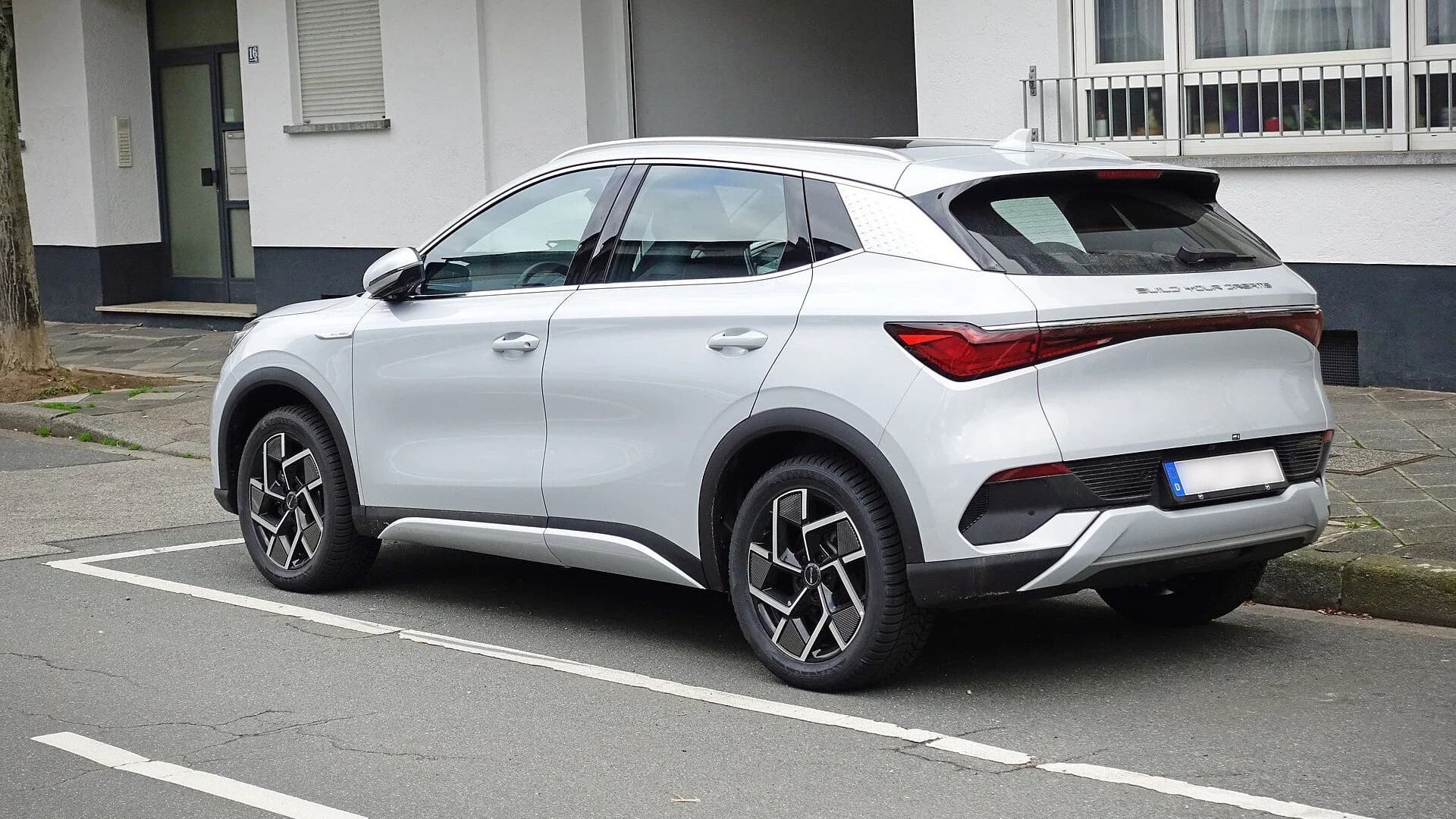 A silver BYD Atto 3 electric SUV parked on a city street in profile view.
