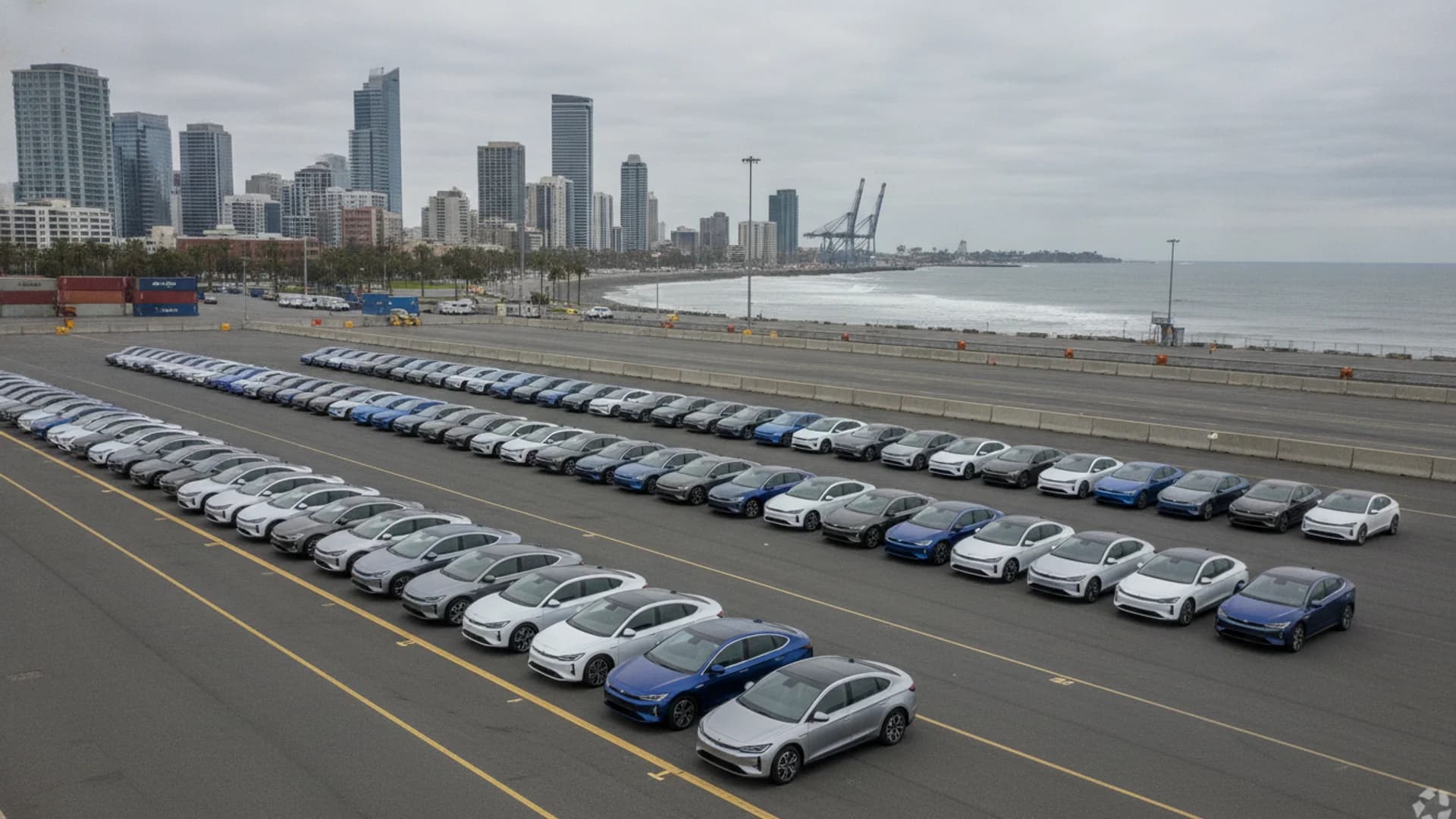 Rows of electric vehicles at an import terminal with a coastal city skyline