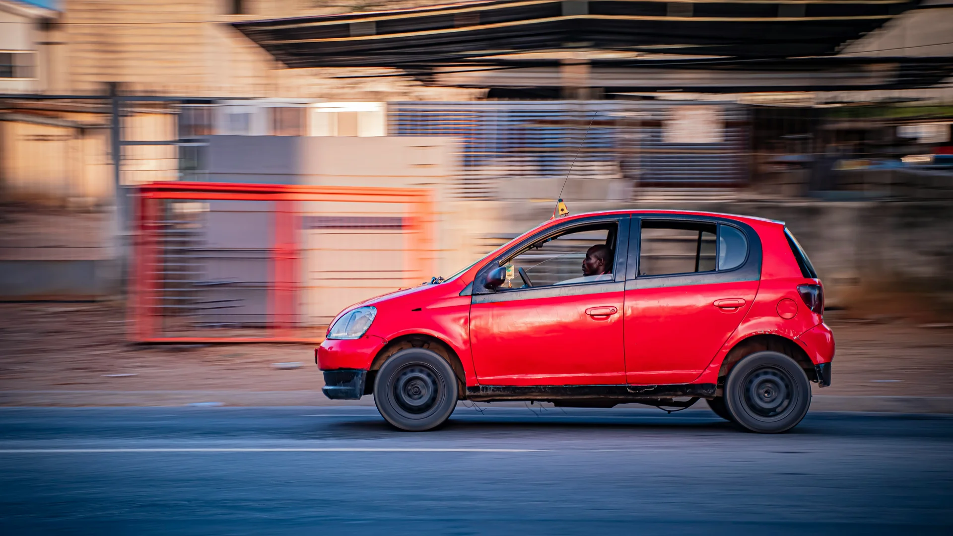 A red car driving on a road with motion blur