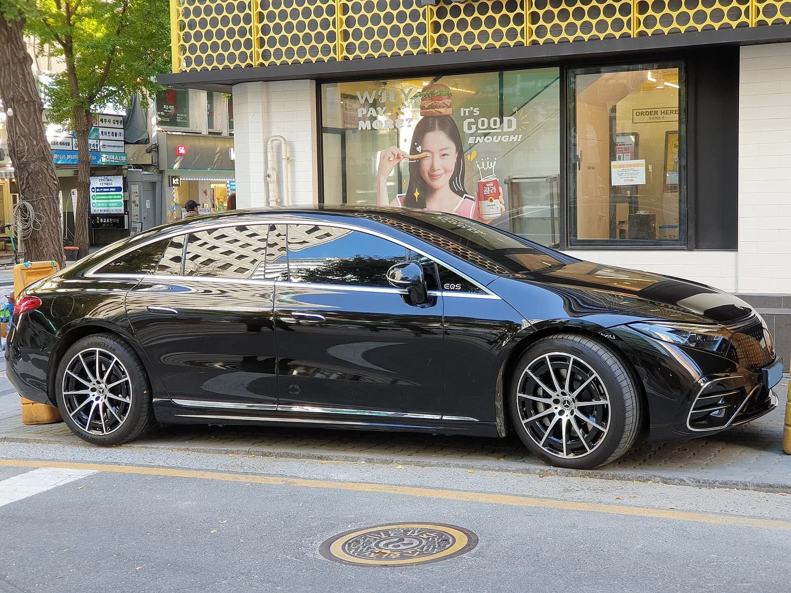 Black Mercedes-Benz EQS electric sedan in side profile on a city street