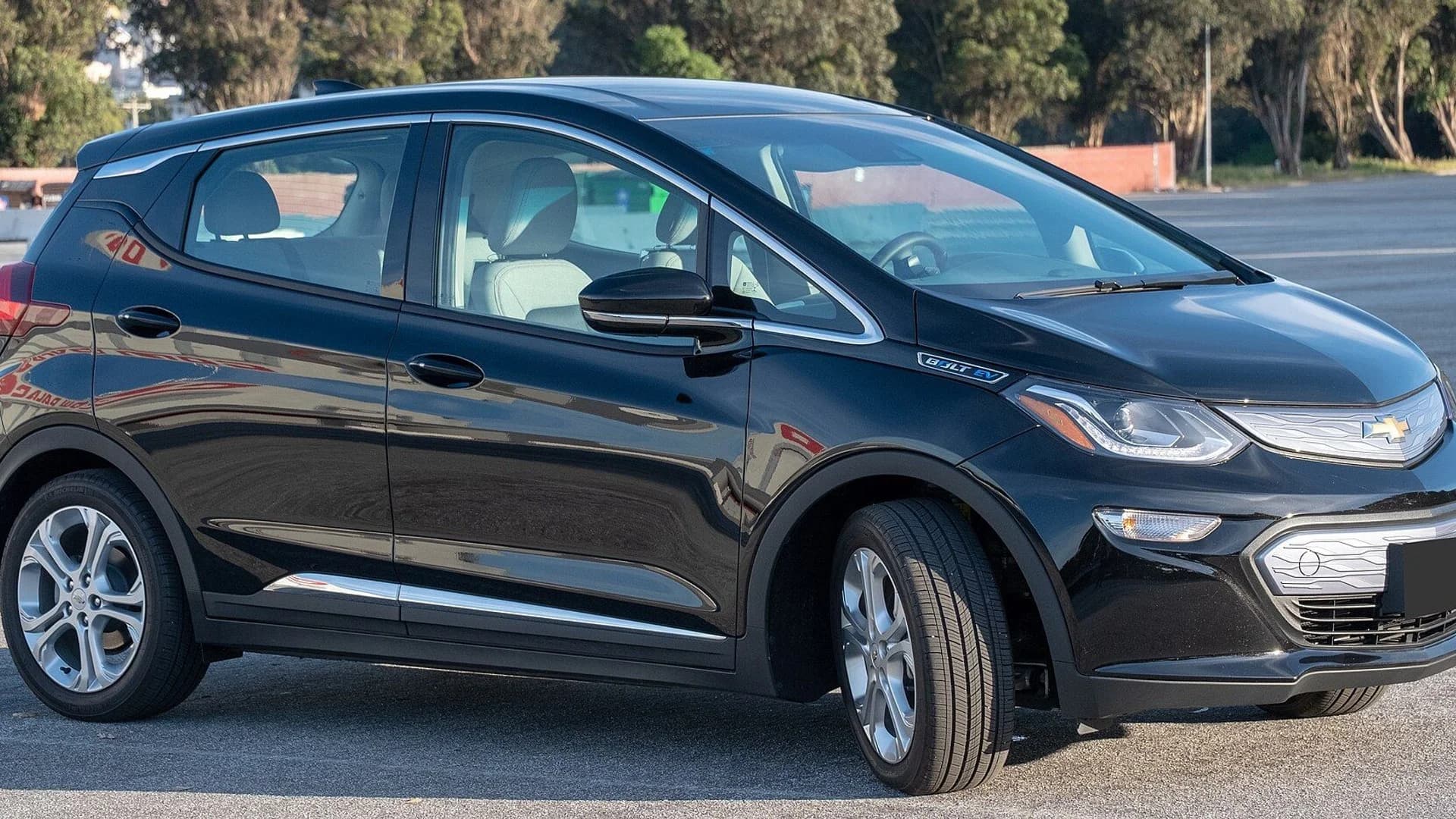 A black Chevrolet Bolt EV parked on a paved outdoor lot on a sunny day.