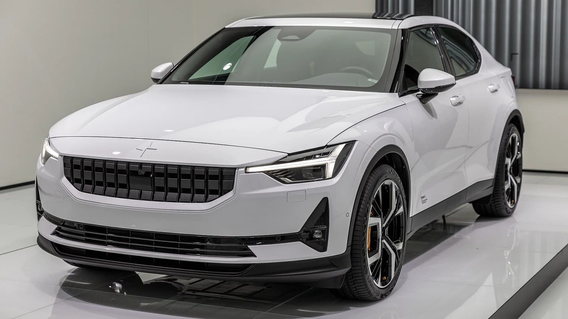 A sleek white Polestar 2 electric car parked inside a brightly lit vehicle showroom.