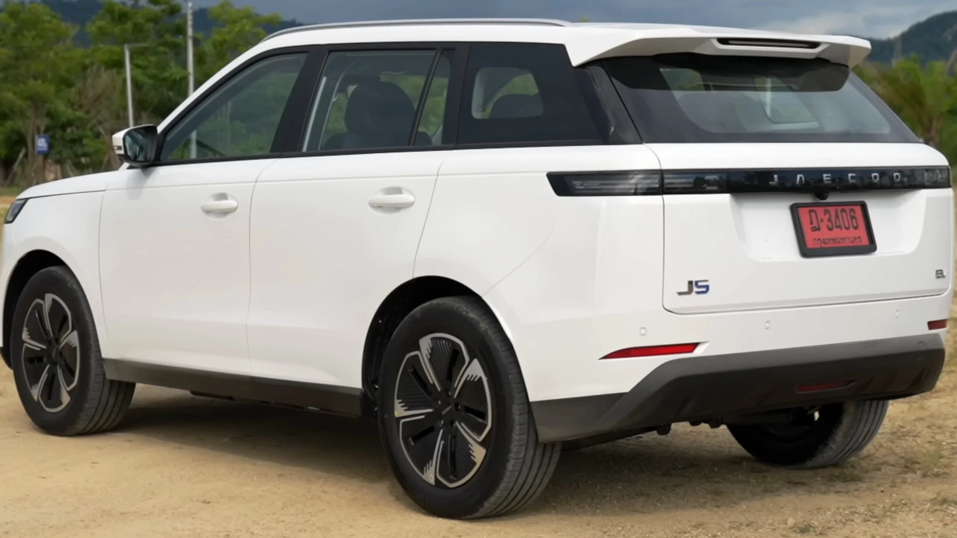 Rear three-quarter view of a white Jaecoo J5 EV parked on an unpaved outdoor surface.