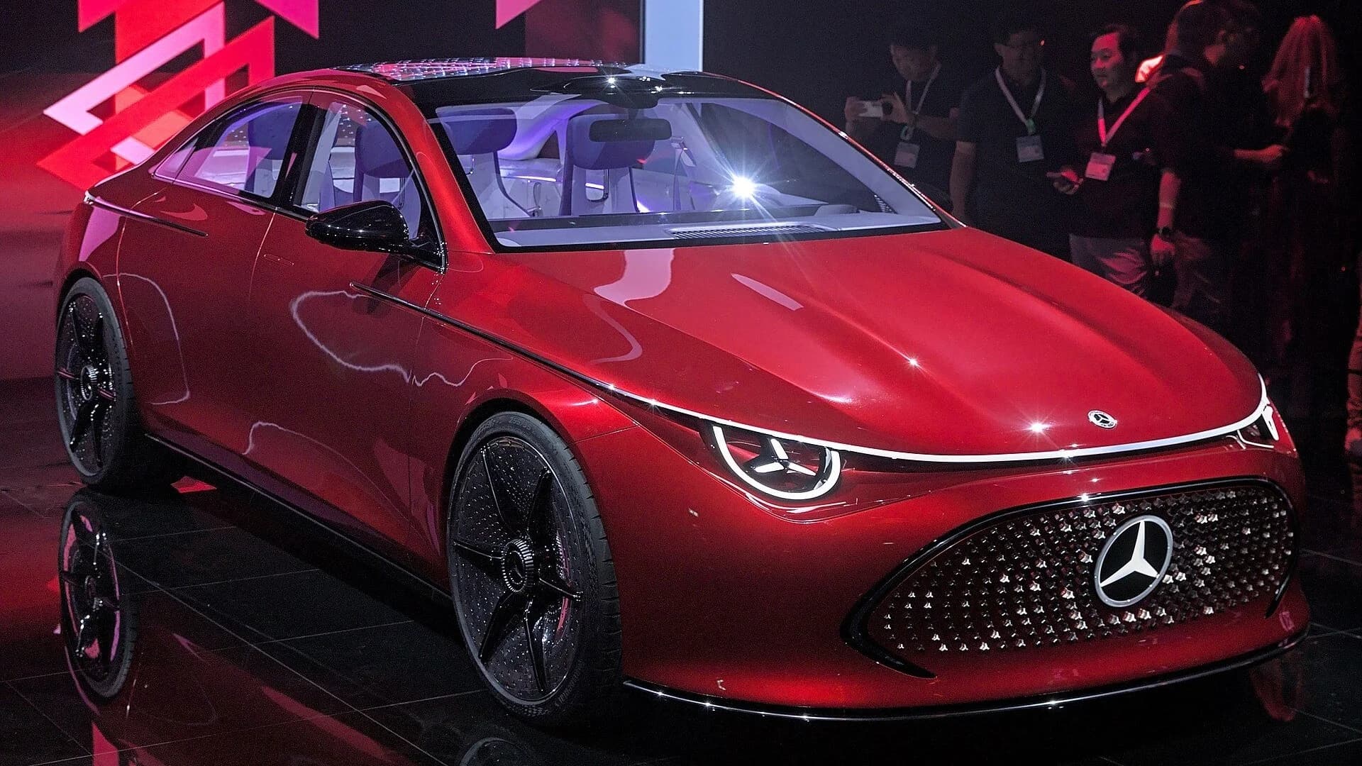 A red Mercedes-Benz Concept CLA Class electric car on display at an auto show.