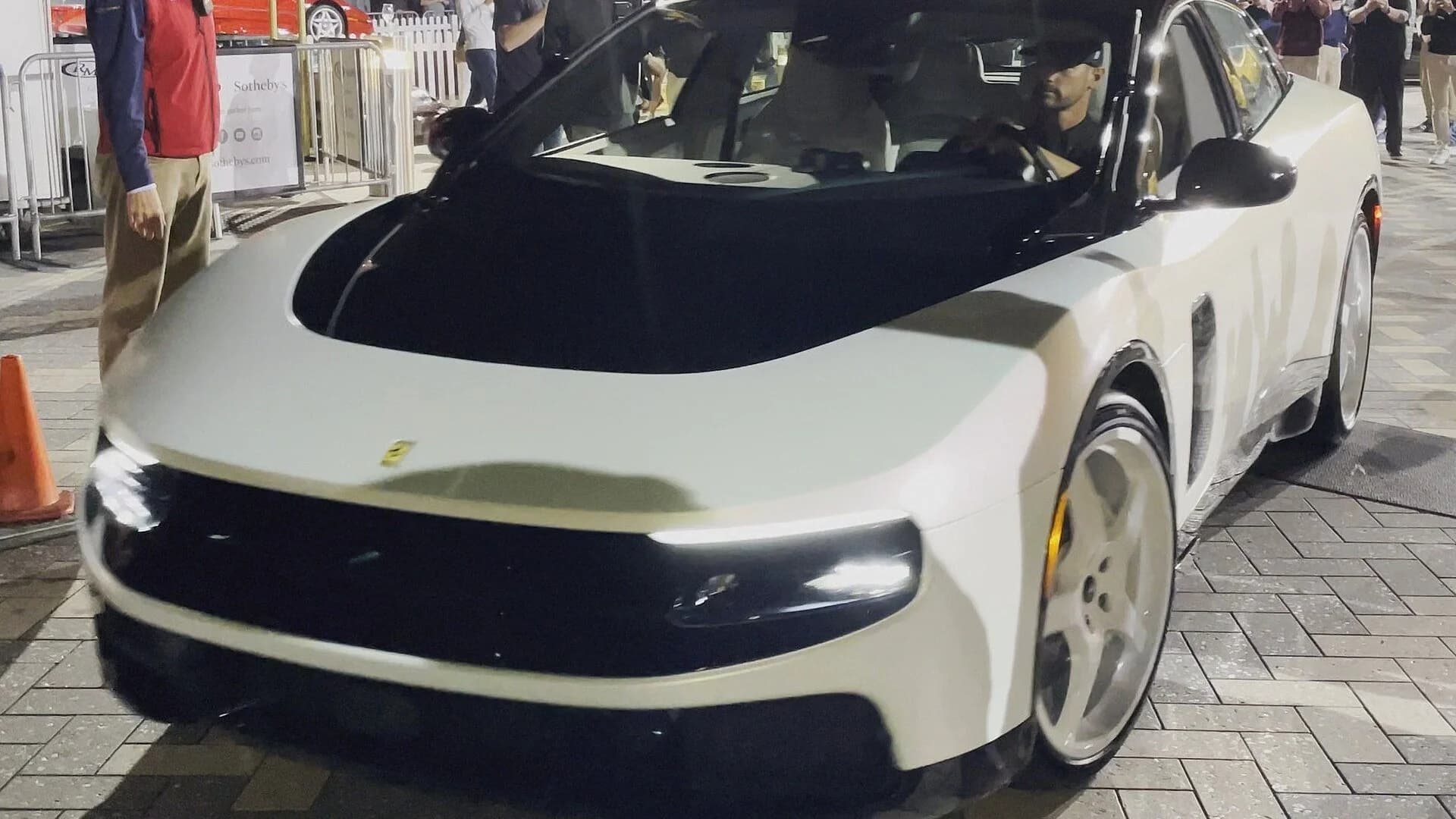 A white Ferrari Luce EV concept car parked outside at night surrounded by people.
