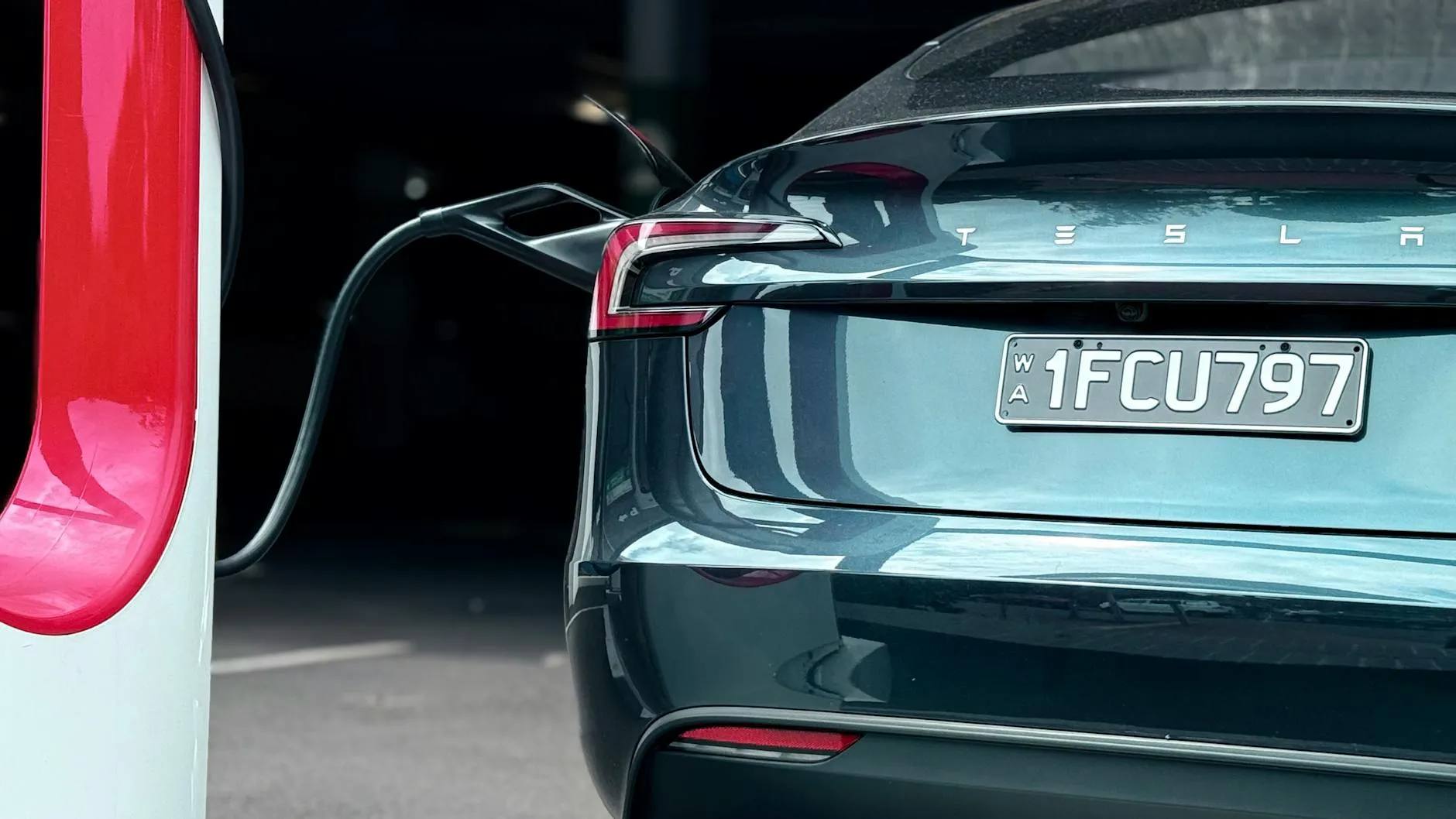 Red electric car parked outdoors near a Canadian winter charging station.