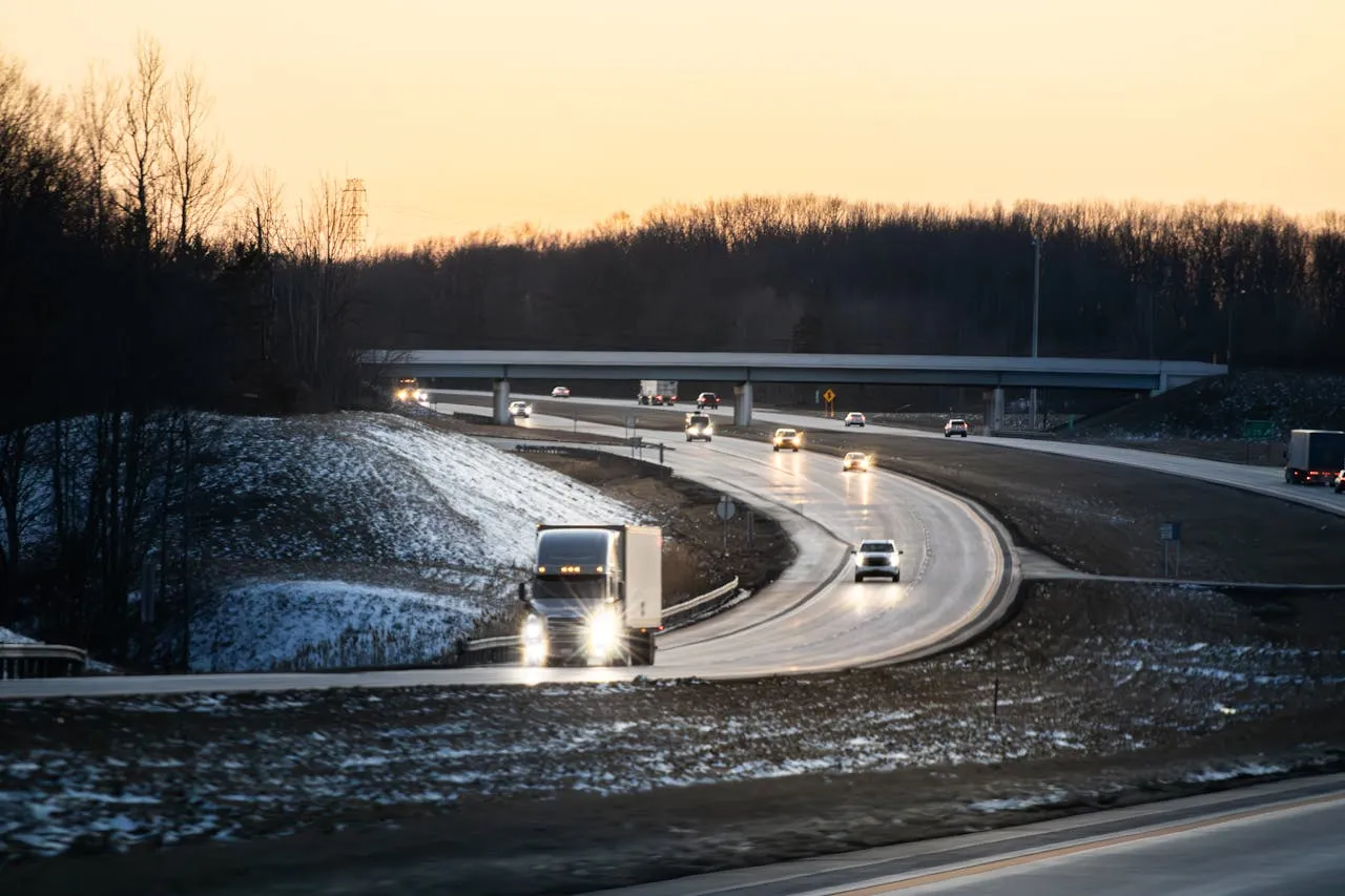 Cars driving on a snowy Canadian highway at dusk during winter conditions