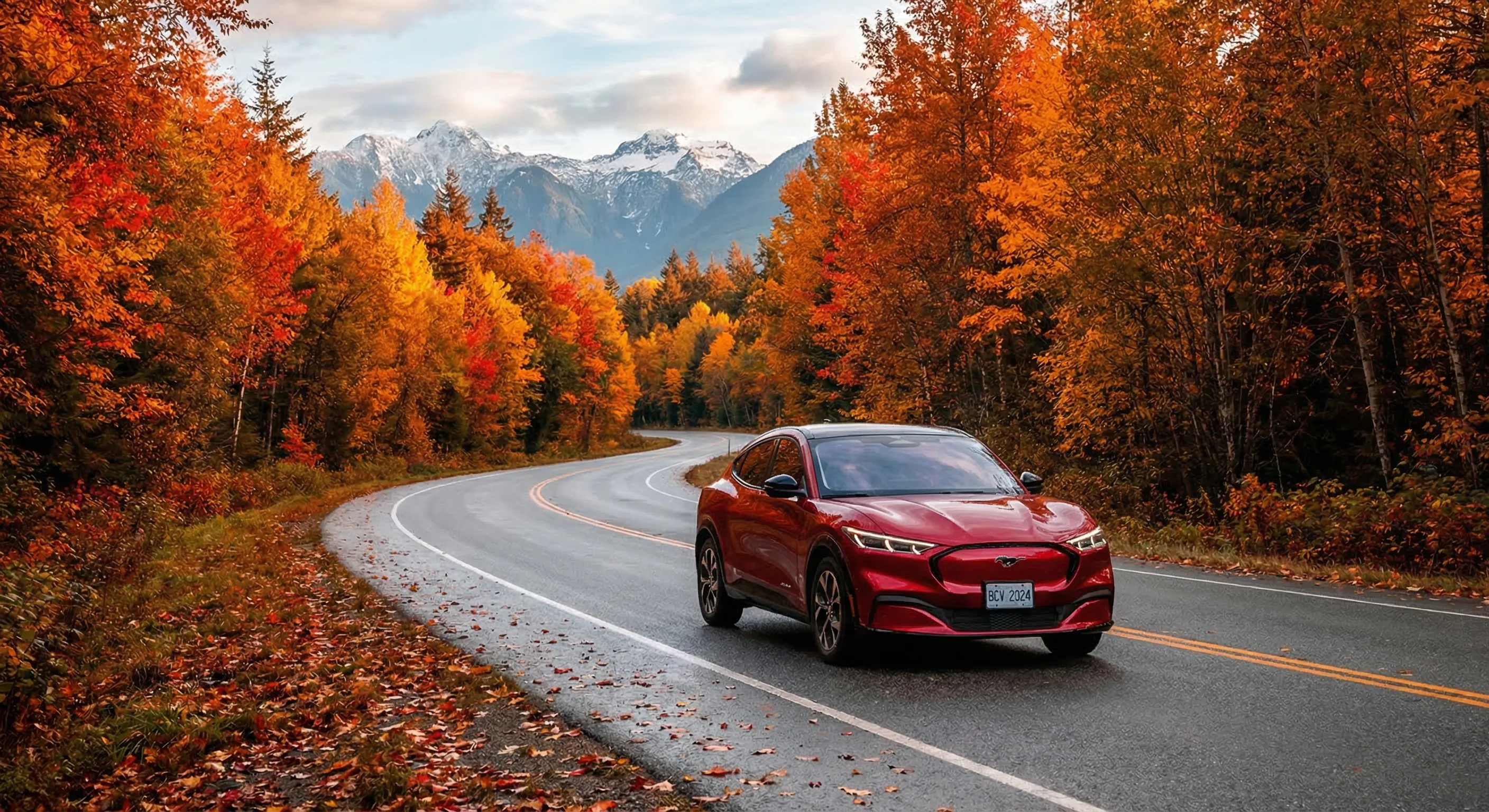 Ford Mustang Mach-E electric crossover on a scenic Canadian highway with autumn foliage in orange and red