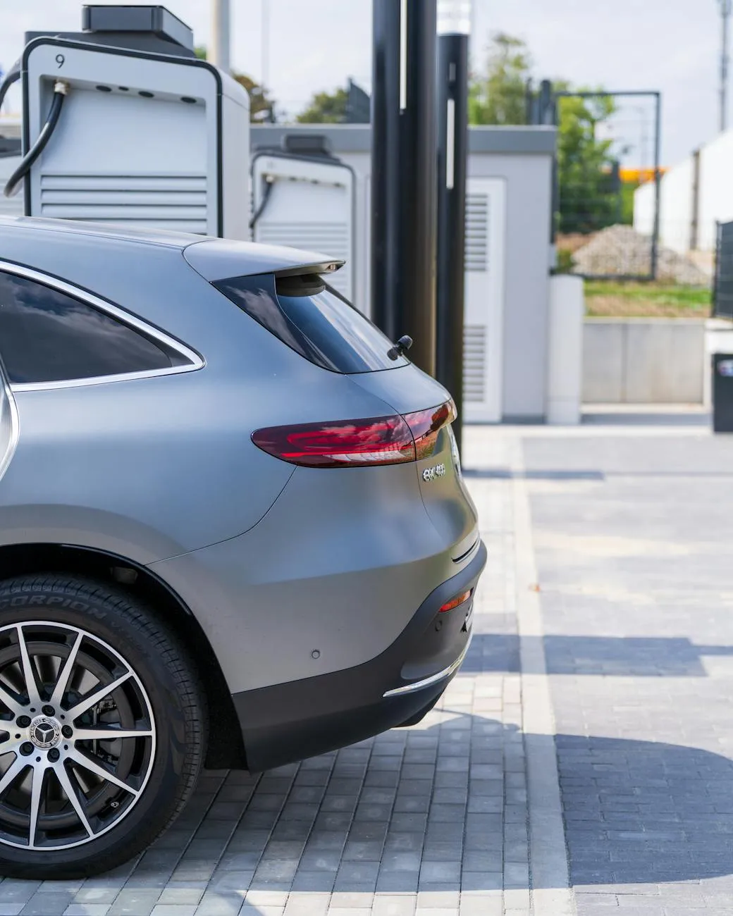 Close-up of a person plugging in an electric car at a charging station outdoors.